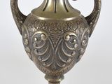 un vase en argent posé sur une surface blanche