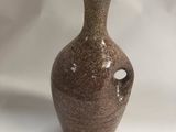 a brown vase that is sitting on a white surface