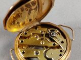 a gold pocket watch that is open on a white surface