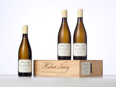 trois bouteilles de vin sont posées devant une caisse en bois