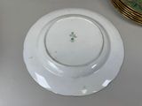 a white plate with a green flower on it on a table