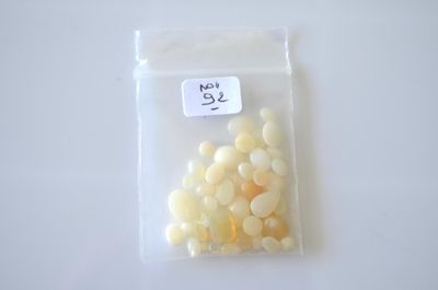 un sac de perles blanches et jaunes posé sur une table blanche
