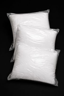 trois oreillers blancs sont emballés dans des sacs en plastique sur un fond noir