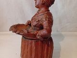 figurine en bois représentant une femme tenant un plateau avec de la nourriture