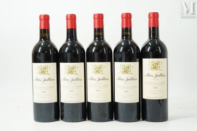 quatre bouteilles de vin rouge sont alignées sur une surface blanche