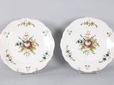 two plates with flowers and birds painted on them on a gray surface