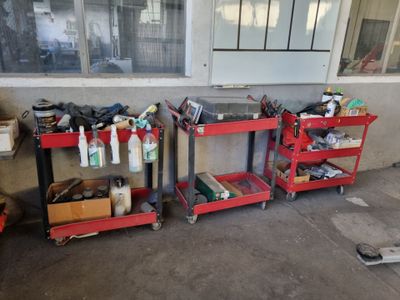 deux chariots rouges chargés d'outils devant un bâtiment