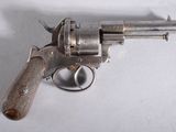 un revolver en argent avec une poignée en bois sur une surface blanche