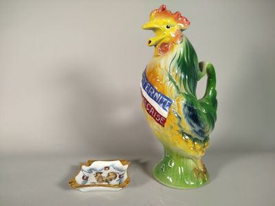 une figurine représentant un coq posée sur une table, à côté d'une assiette