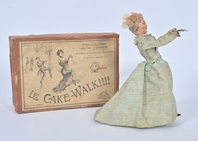 une poupée en robe verte à côté d'une boîte de « cakewalks »