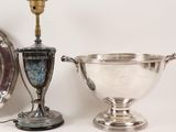 a silver cup and a silver plate with a candle on it