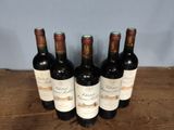 six bottles of wine are lined up on a wooden table