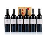 four bottles of red wine in front of a wooden box