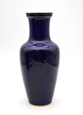 un vase bleu bordé d'or sur fond blanc