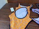 two swimsuits and a pair of glasses on the floor