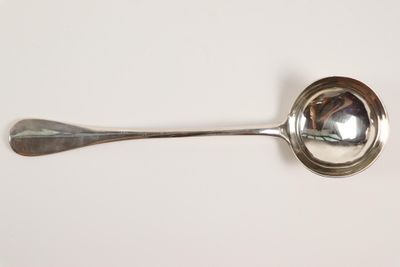 une cuillère en argent avec un manche de cuillère sur une surface blanche