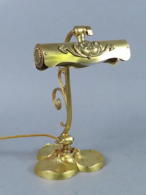 brass plated desk lamp with a gold colored shade and a gold colored base