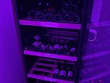 de nombreuses bouteilles de vin dans une cave à vin, sous une lumière violette