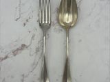 deux cuillères en argent et une fourchette posées sur une table en marbre