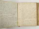 an old open book with writing on it sitting on a table