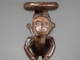 a wooden statue of a monkey with a large head on it ' s head