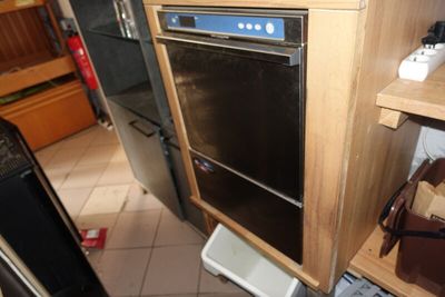 un four noir posé dans une cuisine, à côté d'une poubelle blanche