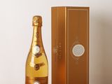 une photo montrant une bouteille de champagne posée à côté d'une boîte sur une table en bois