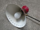une lampe rouge et blanche posée sur un sol en béton