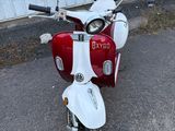 un scooter rouge et blanc garé devant un immeuble