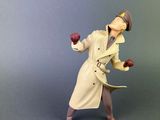 toy figurine of a man in a trench coat and hat holding an apple