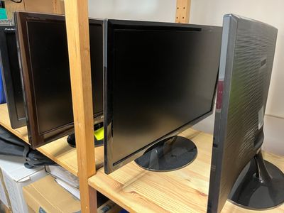 two monitors sitting on a shelf next to each other