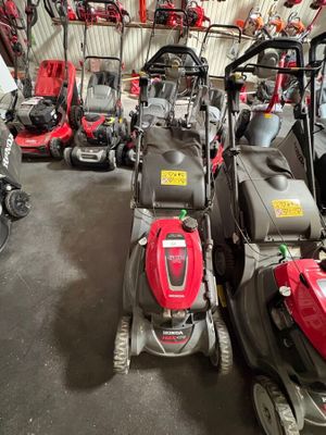 Plusieurs tondeuses à gazon sont alignées dans un garage