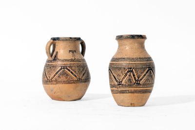 une paire de vieux vases en poterie ornés de motifs sur fond blanc