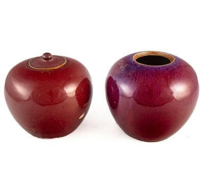 deux vases rouges posés l'un à côté de l'autre sur une surface blanche