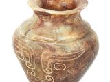 un vase brun orné d'un motif sur une surface blanche