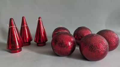 several red christmas balls and cones on a white surface