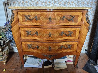 une commode en bois dans une pièce dont l'un des murs est tapissé
