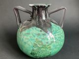 a green vase with a tree on it on a table