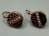 pair of gold tone earrings with pearls on them sitting on a table