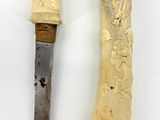 two pieces of carved ivory and a knife on a white surface