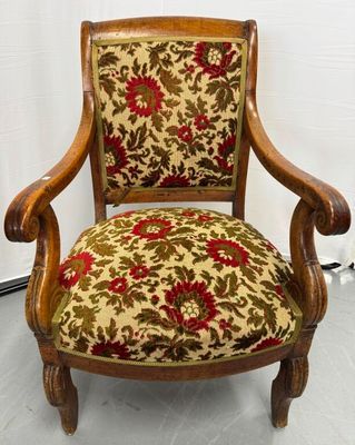 une vieille chaise en bois dont l'assise est recouverte d'un tissu à motifs floraux