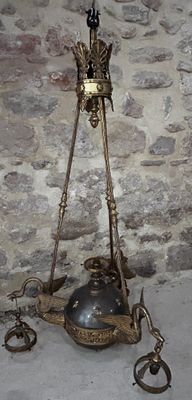 a large metal bell hanging from a chain on a stone wall