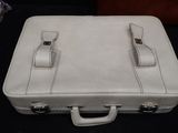 a white leather suitcase sitting on a black surface