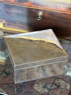 a small box sitting on a glass table next to a chest of drawers