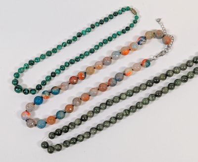 a close up of a group of necklaces on a white surface