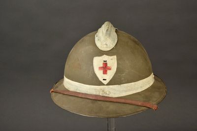 un casque orné d'une croix rouge, posé sur un support