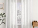 Les rideaux gris et blancs sont suspendus au rebord de la fenêtre.
