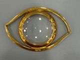 a close up of a gold plated eye broochle on a white background