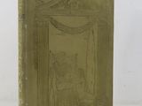 an old book with a gold cover on a white surface
