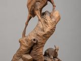 sculpture représentant un chien sur un tronc d'arbre, avec un chat posé dessus